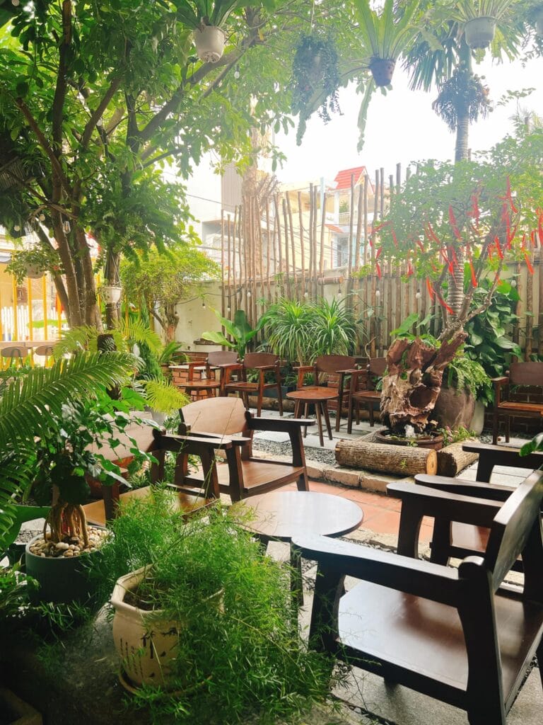 Không gian bên trong Nhàn Cafe Đà Nẵng với bàn gỗ và cây xanh, mang lại cảm giác yên tĩnh và thư giãn